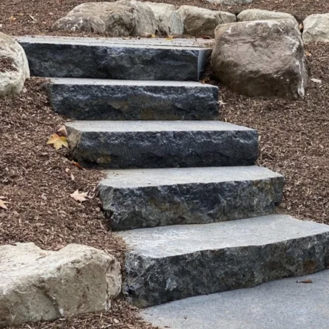 Closeup of Sturgeon River Black Granite step treads set in mulched landscape