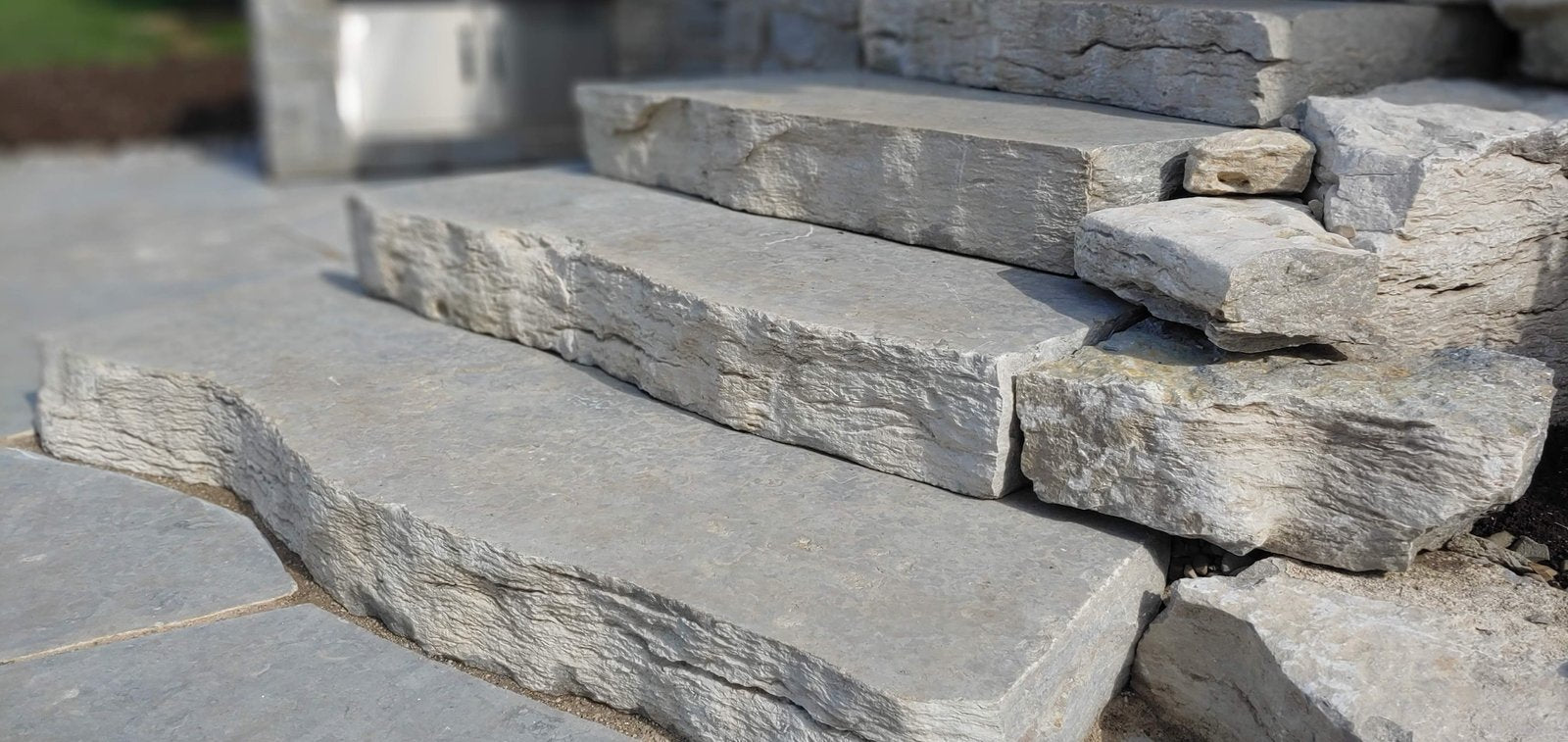 Closeup of Weatheredge Limestone live-edge steps beside stacked armor stone